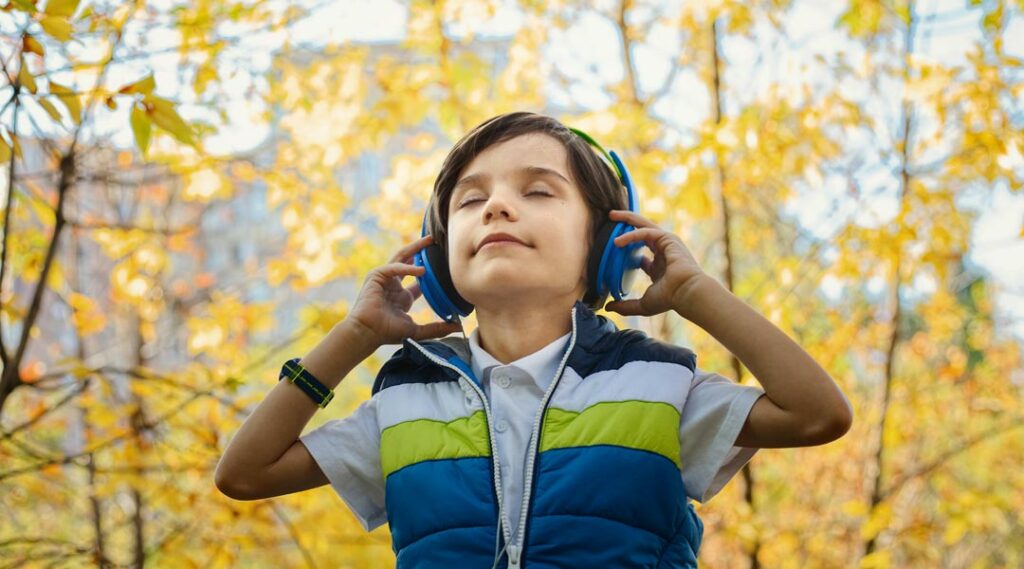 criança com auriculares a escutar música na natureza